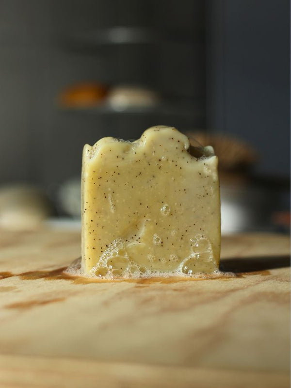 Savon exfoliant NOSTALGIA aux pépins de raisin, avec sa mousse, sur une planche en bois